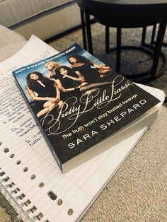 a book sitting on top of a notebook next to a table with a chair in the background