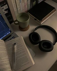 an open book sitting next to headphones on top of a desk