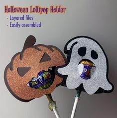 two halloween lollipop holders with candy in them