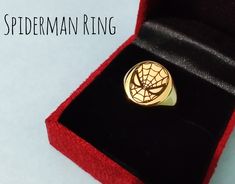 a spiderman ring in a red velvet box with the word,'spiderman ring'written on it