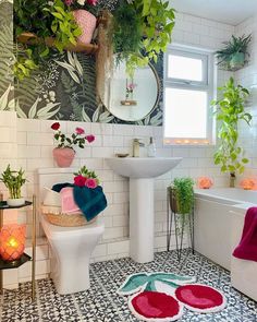 a bathroom with plants on the wall and a rug in front of the tub, sink, toilet and mirror