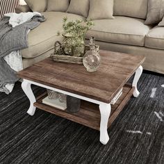 a living room with a couch, coffee table and two vases on the end tables