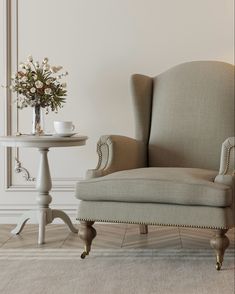 a chair sitting next to a table with a vase on it