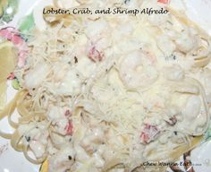 pasta with shrimp, crab and shrimp alfredo on a white plate topped with lemon wedges