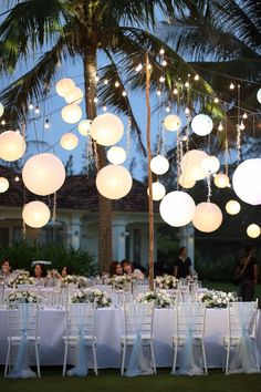 an outdoor wedding reception with paper lanterns hanging from the ceiling