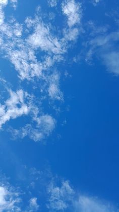 an airplane is flying high in the blue sky with some clouds above it and below