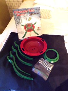 there is a red bowl and green scissors on the bed with a book about christmas bulbs