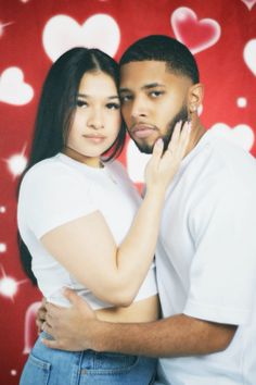 a young man and woman embracing each other in front of hearts on a red background