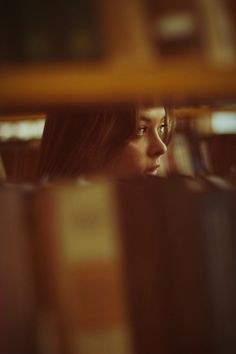 a woman looking out from behind a book shelf with books on it's shelves