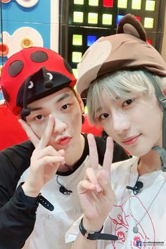 two young men posing for a photo with one holding up the peace sign while the other is wearing a ladybug hat