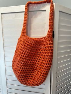 an orange crocheted handbag hanging on a white door