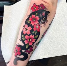 a black cat with red flowers on it's arm