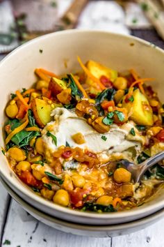 a white bowl filled with food on top of a wooden table next to utensils