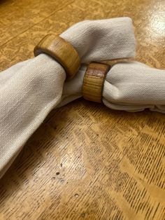 a napkin with a wooden ring on it sitting on top of a wood table next to a knife