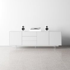 two speakers are sitting on top of a white cabinet in the middle of a room