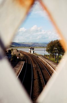 the reflection of a train track in a mirror with a view of water and hills