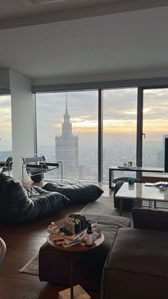 a living room filled with furniture and large windows overlooking the cityscape at sunset