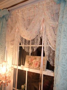 the window is decorated with beaded curtains and pink flowers on it's valance