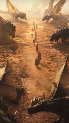 a group of people walking down a dirt road next to dragon like structures in the desert