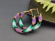 ✔️ Enhance your boho and hippie style with these exquisite handmade beaded hoop earrings. Made from high-quality glass materials, these earrings feature a stunning combination of green and purple beads that are meticulously handcrafted to create a unique and eye-catching design. With a size of 1.6 inches, they are the perfect accessory to add a touch of bohemian charm to your everyday outfits or special occasions. ✔️ Highlights: 1. Handmade Item: These hoop earrings are lovingly handmade, ensuri Bohemian Beaded Small Hoop Earrings With Ear Wire, Bohemian Small Hoop Beaded Earrings With Ear Wire, Small Hoop Beaded Earrings With Tiny Beads For Festival, Festival Small Hoop Earrings With Tiny Beads, Bohemian Hoop Beaded Earrings With Colorful Beads, Bohemian Hoop Earrings With Dangling Beads, Bohemian Hoop Earrings With Dangling Round Beads, Festival Hoop Earrings With Tiny Beads, Bohemian Small Hoop Beaded Earrings With Dangling Beads