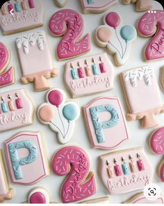 decorated birthday cookies are arranged on a white tablecloth with pink and blue icing