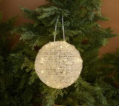 a christmas ornament hanging from the top of a tree with lights on it