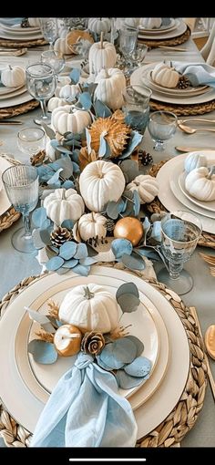 the table is set with white pumpkins and blue flowers on it, along with silverware