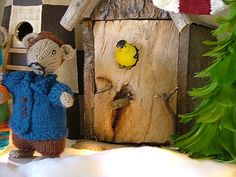 two knitted mice standing in front of a birdhouse