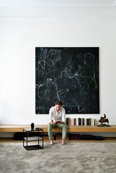 a man sitting on a bench in front of a blackboard