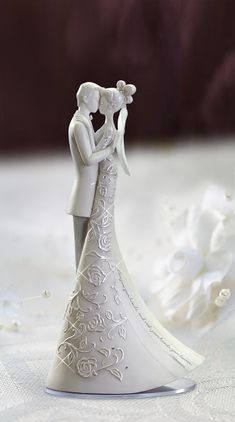 a wedding cake topper with a bride and groom kissing