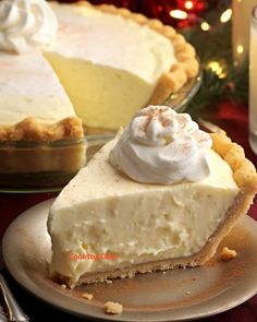 a slice of cheesecake on a plate next to a glass bowl with whipped cream