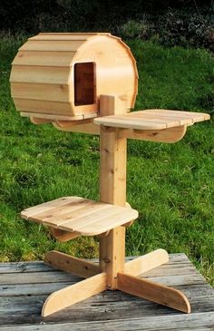 a wooden bird house on a stand in the grass