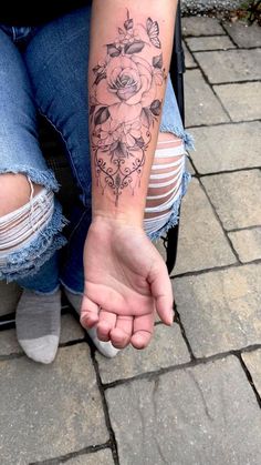 a woman with a flower tattoo on her arm sitting in a stroller and holding the hand of another person