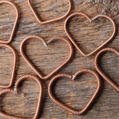 four copper heart shaped coils sitting on top of a wooden table