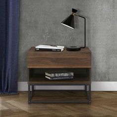 a table with a lamp and books on it in front of a gray painted wall