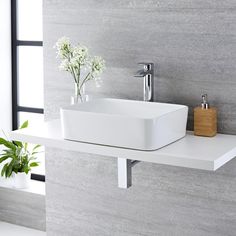 a white sink sitting on top of a counter next to a plant in a vase