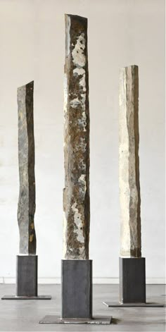 three tall metal sculptures sitting next to each other on top of pedestals in front of a white background