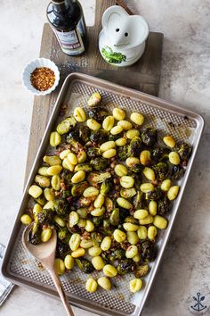 roasted brussel sprouts on a baking sheet with a wooden spoon next to it