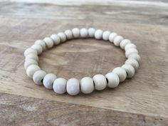 This men's wood beaded bracelet with light, cream-colored wood beads is one of the most popular styles that we offer. The beads are made of real wood, are round/spherical in shape and are 6mm in width. The bracelet is made with strong, durable stretch elastic cord, which allows it to stretch over your hand and onto your wrist. With multiple sizes available, these unisex bracelets are made to fit any size of wrist perfectly - whether you like your bracelet loosely hanging or tight to your wrist, we have you covered. Our variety of sizes ensure that this bracelet will comfortably fit the modern man or woman.  To determine your size, take a string and wrap it around your wrist. Hold the string next to a ruler or measuring tape to see the length. Add .25" to the measured length if you like you Beige Bracelets With Wooden Round Beads, Beige Wooden Beaded Bracelets, Natural Wood Beaded Bracelets, Natural Wood Beaded Bracelets With Round Beads, Beige Beaded Bracelets With Round Beads, Beads For Men, Wood Bead Bracelet, Wrist Wear, Unisex Bracelets