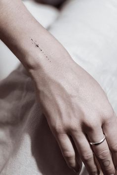 a person's hand with a tiny tattoo on it, resting on a bed