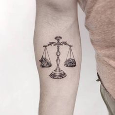 a person with a tattoo on their arm holding a scale and two rocks in front of them