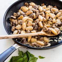 a skillet filled with mushrooms and spinach on top of a white countertop