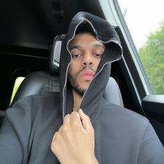 a man wearing a hoodie in the back seat of a car