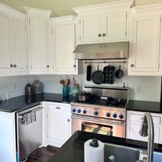 a kitchen with white cabinets and black counter tops