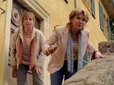 two women are walking up the steps to a house with their hands in each other's pockets