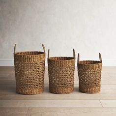 three woven baskets sitting on top of a wooden floor