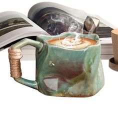 a coffee mug with steam coming out of it sitting in front of an open book