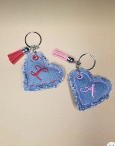 two heart shaped keychains with tassels on them, one has the letter k and the other has an initial