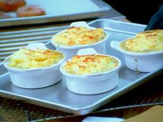 four white dishes filled with food sitting on top of a metal tray