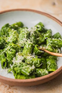 a white bowl filled with green vegetables on top of a table